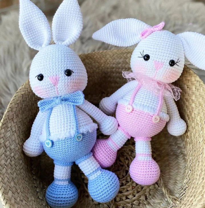 Hasır sepette mavi ve pembe tulumlu iki tığ işi amigurumi tavşan